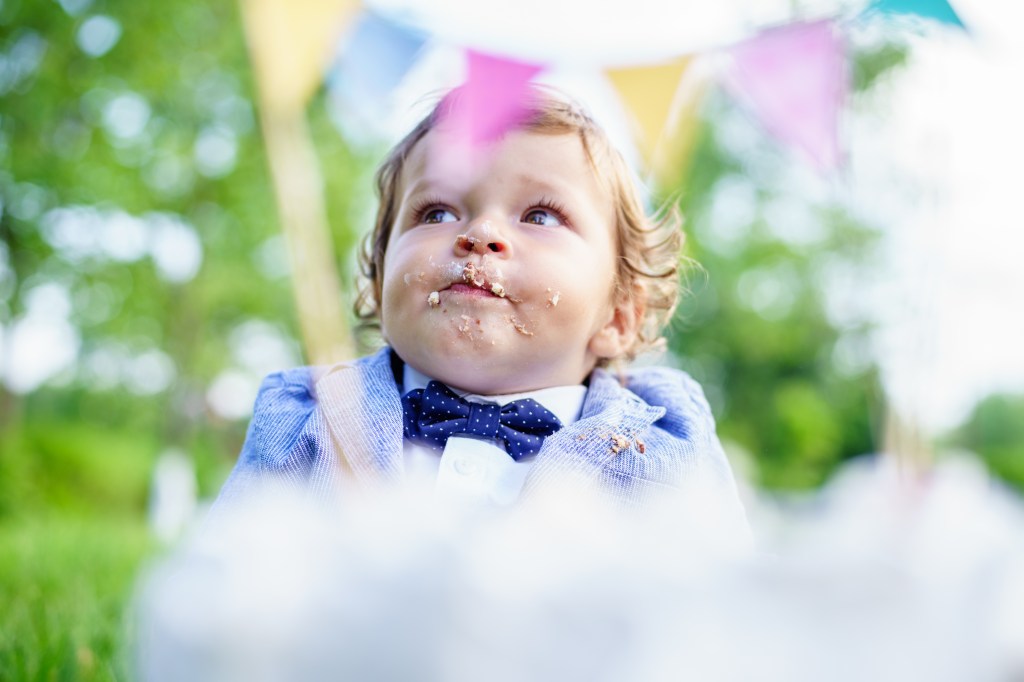 The little boy with cake on his face on his first birthday party.