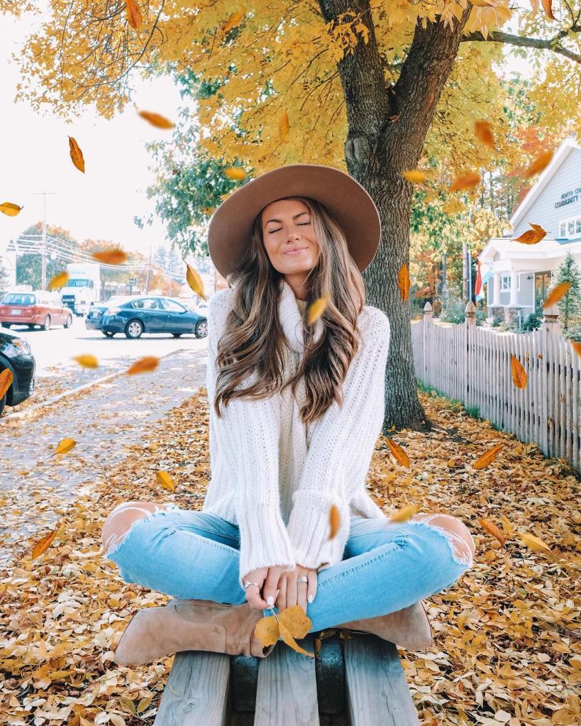 Woman in autumn clothing sitting on a park bench.