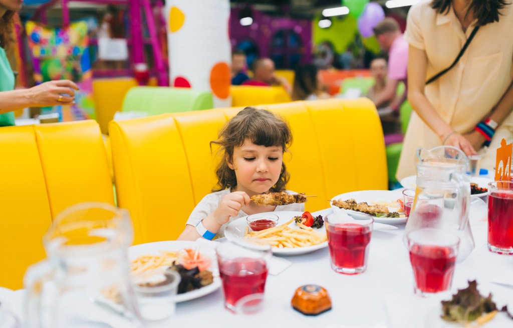 Girl who eats shish kebab and chips in a restaurant.