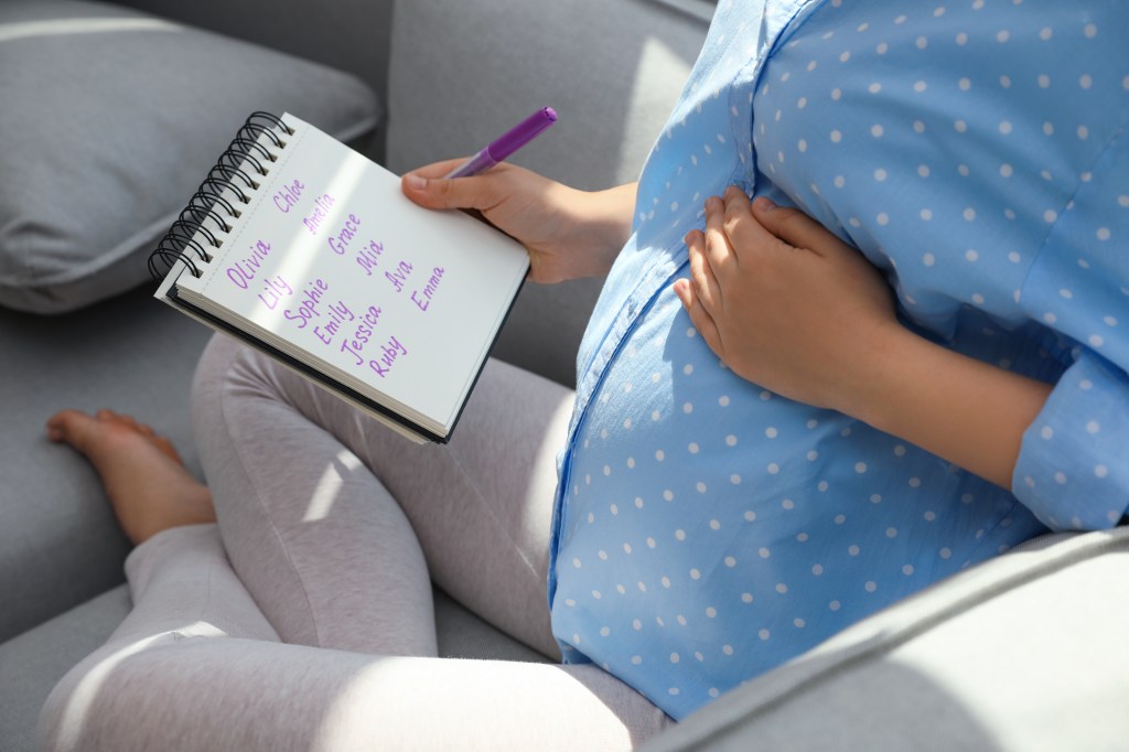 Pregnant woman who looks at the names of children in a notebook.